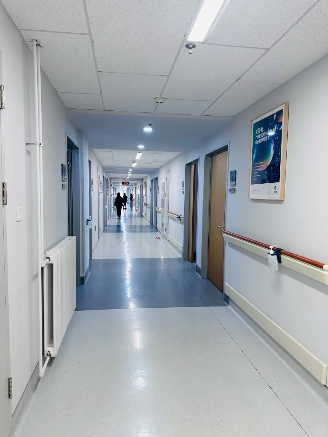 Clean wide hospital corridor with safety handrails and bright lighting