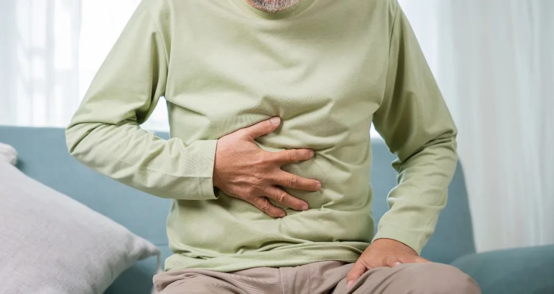 Elderly patient holding abdomen in pain, illustrating acute abdominal symptoms of persistent pain, distension, and vomiting